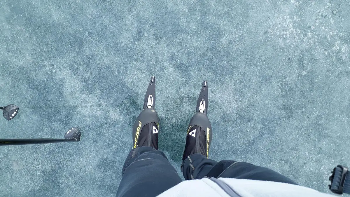 Looking down at skates on clear black ice
