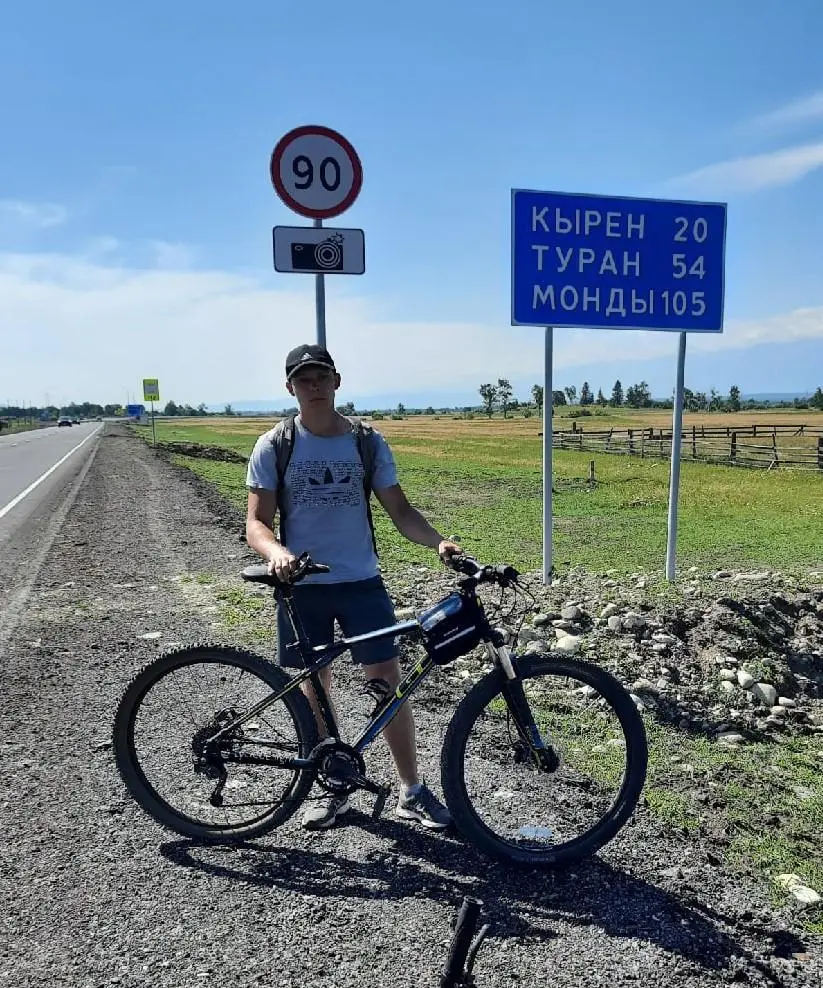On a bike at a road sign in the Tunka valley, Siberia