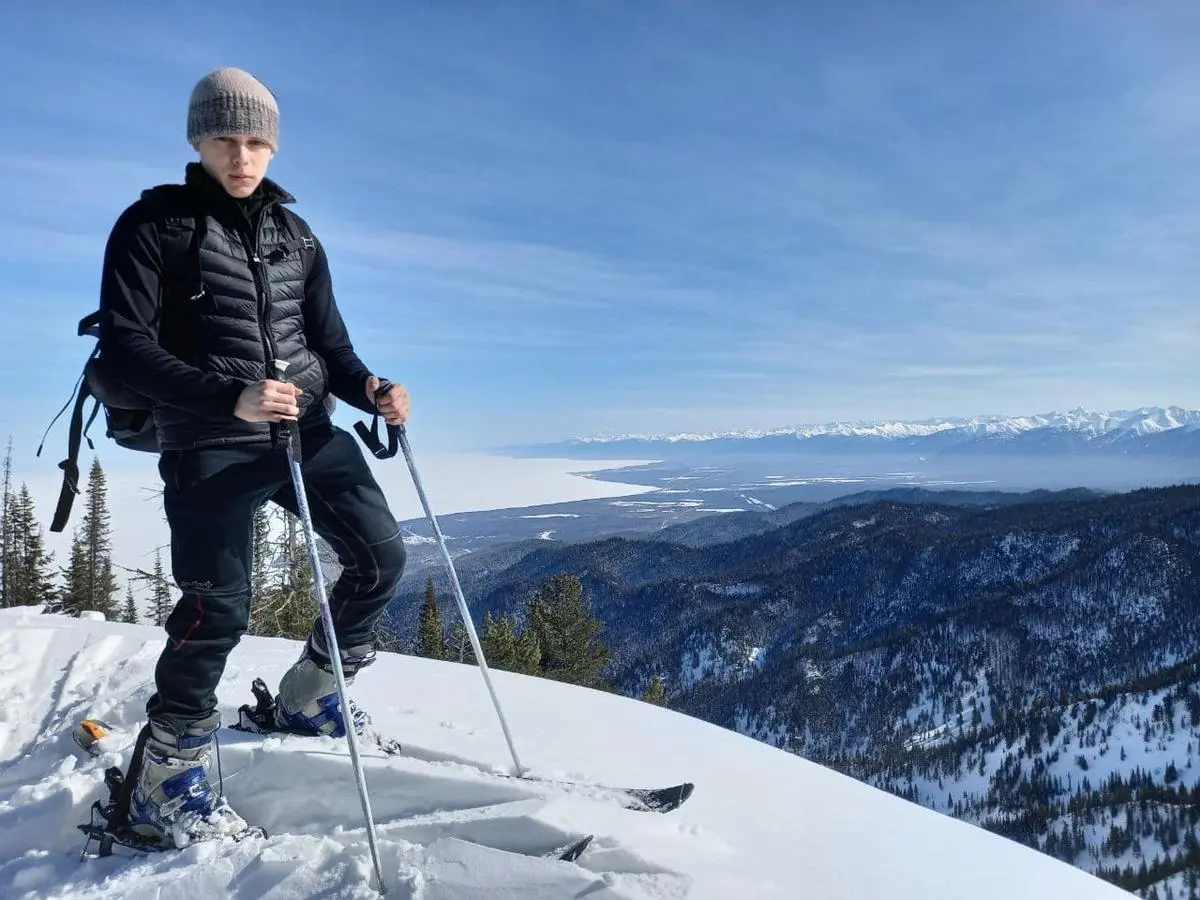 Ski touring on a ridge, mountains and a frozen lake below