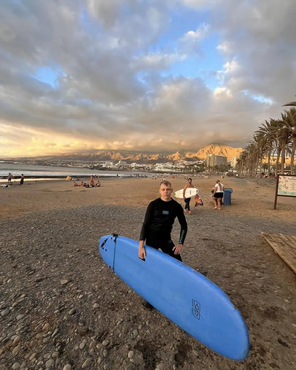 Carrying a surfboard up the beach at dusk
